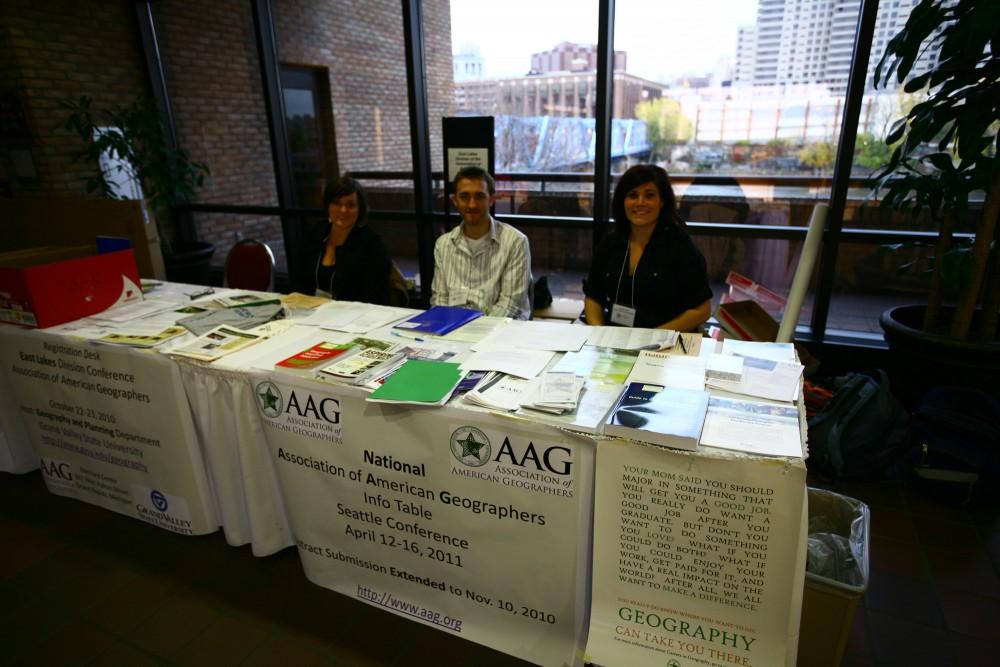 Amanda Moore, Matthew Kapteyn, and Kendall Gilbert sit at the registration and information booth at East Lakes Division Association of American Geographers Conference. The event was hosted by GVSU at the Eberhard Center