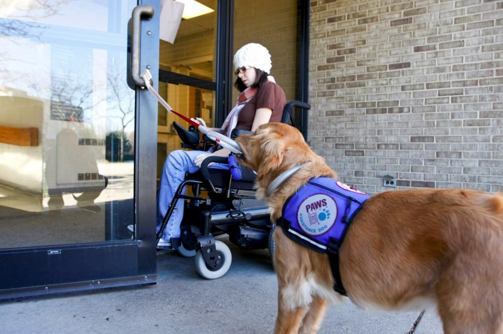 Ashley Wiseman enters a door that is held open by her guide dog Maui.