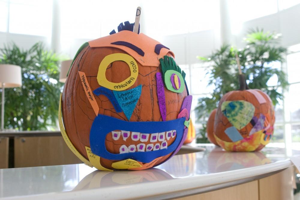 Pumpkins sit on display in the Cook-DeVos Center for Health Sciences building in downtown Grand Rapids. Decorated pumpkins are on display in the lobby in a competition between members of the inaugural SLP 302 course. The pumpkins are decorated in a manner to label the facial and cranial bones.