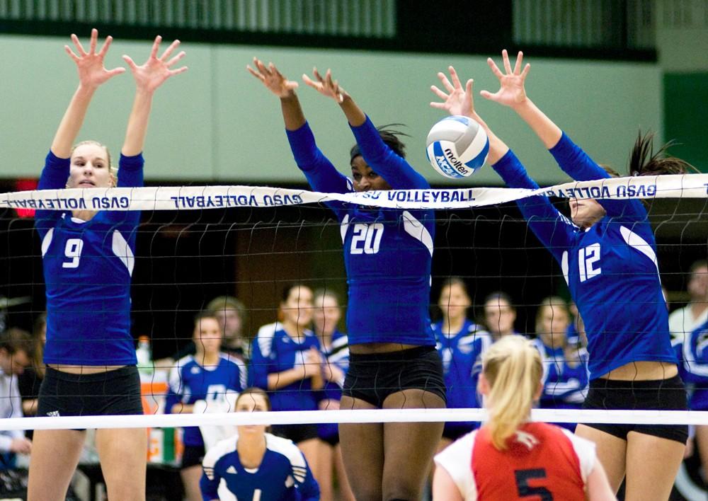 Krysta Kornack, Eno Umoh, and Leslie Curtis spring to the air in attempt to block the ball