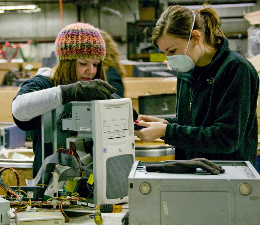 Freshman Martha Schmitt and Sophomore Megan Boundy take apart a computer at the day of service