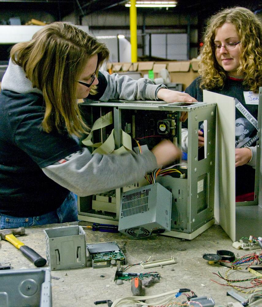 Senior Amanda Alkema and graduate student Jen Koth take apart a computer while they volunteer at Comprenew