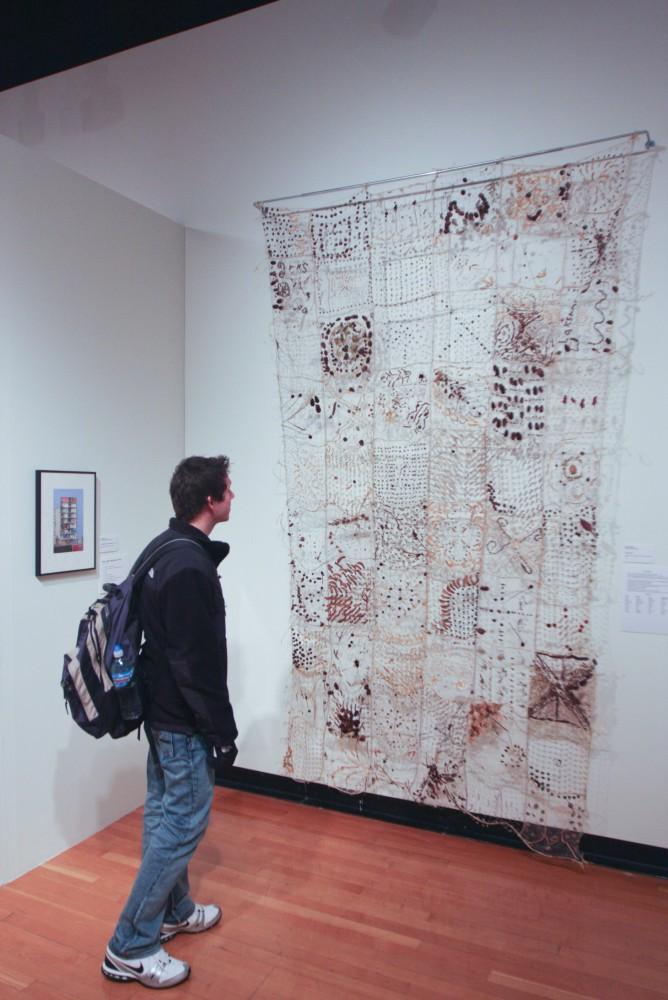 Sandro Sgambati admires the artwork on dispaly at the Multimedia III faculty show in GVSU's Art Gallery