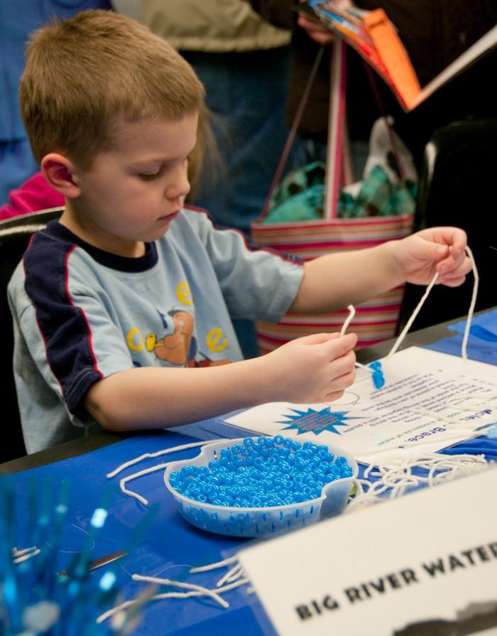 Ben Kellerman, 6, works on a molecular bracelet at Super Science Saturday