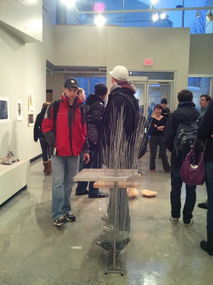 Students peruse the Landed exhibit held in the Padnos Student Gallery in the Calder Art Center