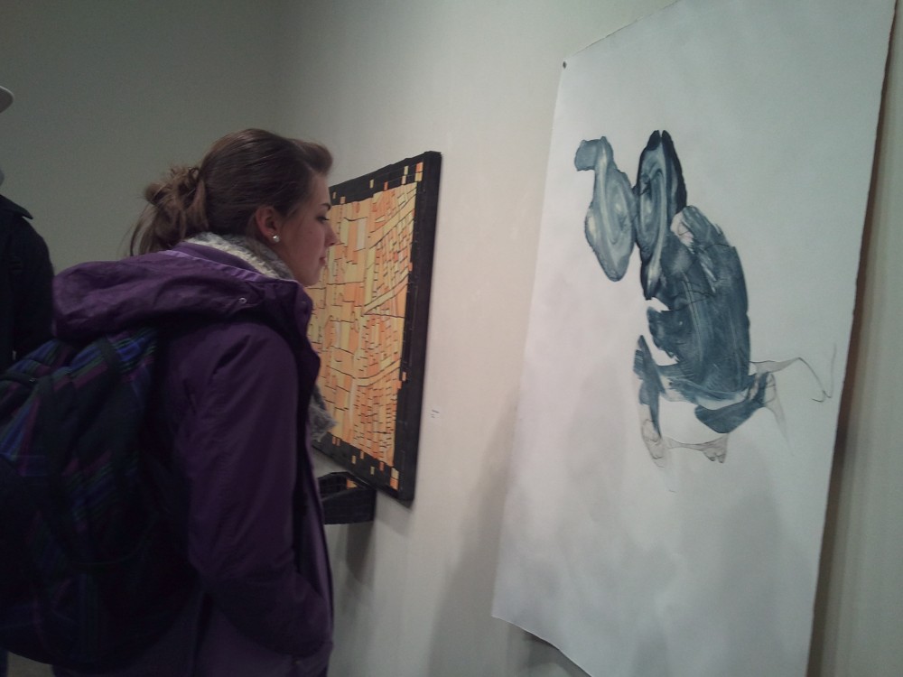 Fresman Samantha Stevens engages with a piece by student artist Julia Victor entitled Vortex at the Landed exhibit. 