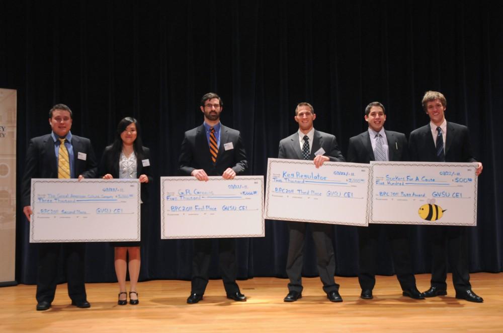 Winners pose with their checks on stage at the 4th Annual Business Plan Competition.