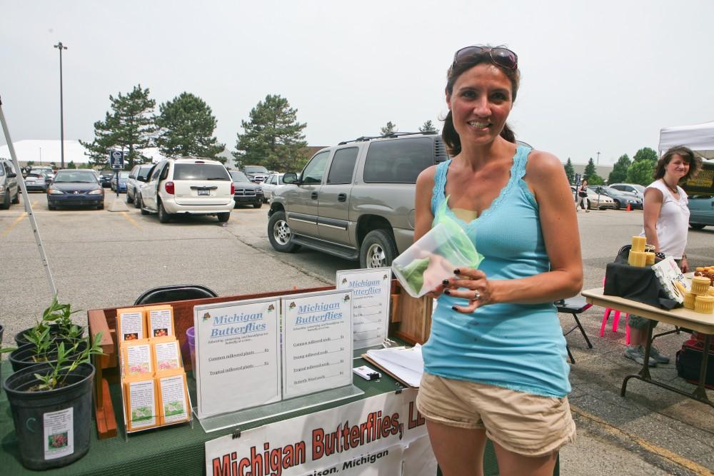 Holli Ward, a Grand Valley State University alum, poses above at her Michigan Butterflies booth at the GVSU Farmers Market, which will run through September in parking lot F. 