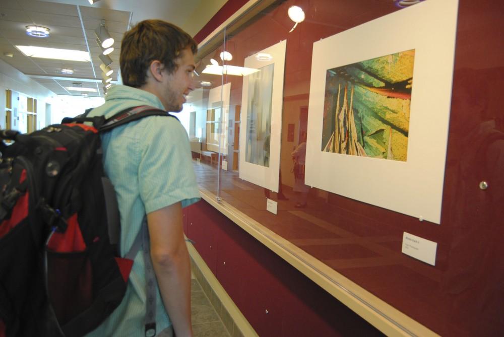 GVL/ Rane Martin
5th year senior Adam Moyer admires the late Robert Koropp's artwork  currently on display on the Red Wall Gallery in Lake Ontario Hall.