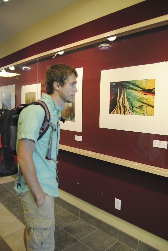 GVL/ Rane Martin
5th year senior Adam Moyer admires the late Robert Koropps artwork  currently on display on the Red Wall Gallery in Lake Ontario Hall.