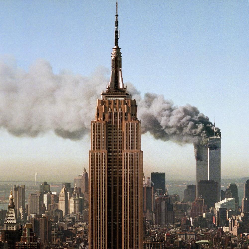 With the Empire State Building in the foreground, the Twin Towers of the World Trade Center burn after being struck by two hijacked airliners, Tuesday morning, Sept. 11, 2001. Photo shot from the Rainbow Room atop 30 Rockefeller Plaza in New York. (AP Photo/Marty Lederhandler)