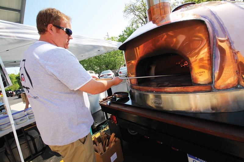 GVL / Robert Mathews
Matt Parrott from Standard Pizza Co. working his pizza oven at the Fulton Street Farmers Market. 