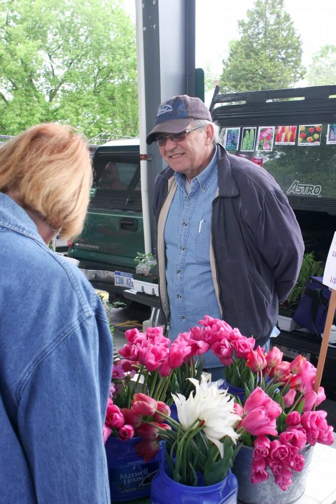 GVL / Eric Coulter
Sparta native Tim Daniels helps a customer with flower selection during the opening day of the Farmers Markert on Fulton. Daniels and his wife have started selling flowers and plants grown at their home as a hobby.