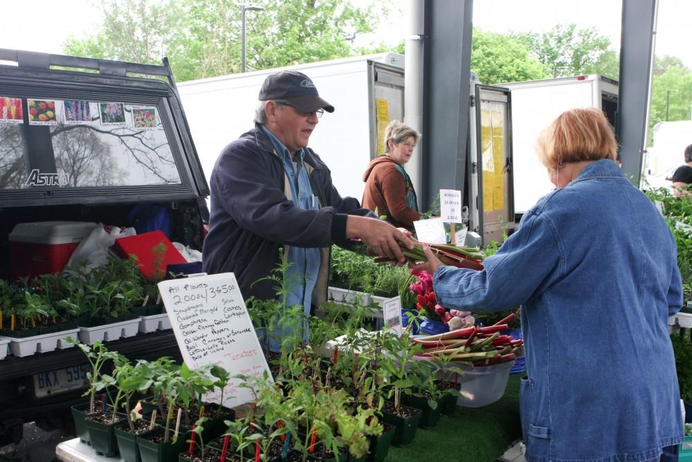 GVL / Eric Coulter
Sparta native Tim Daniels helps a customer with flower selection during the opening day of the Farmers Markert on Fulton. Daniels and his wife have started selling flowers and plants grown at their home as a hobby.