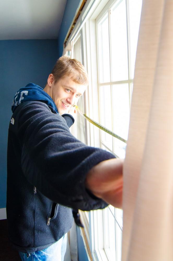 GVL/Bo AndersonSenior Chris Koppenaal works to measure a window in the Wesley House as part of an energy audit.