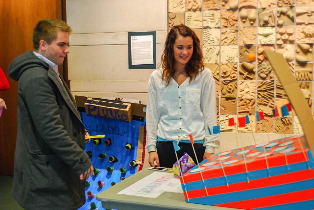 GVL / Hannah Mico. Junior Ali McEldowney (right) constructed a game as part of Professor Kilbournes LIB100 Class project to take on the Cardboard Challenge; here she is shown watching another student play her game.