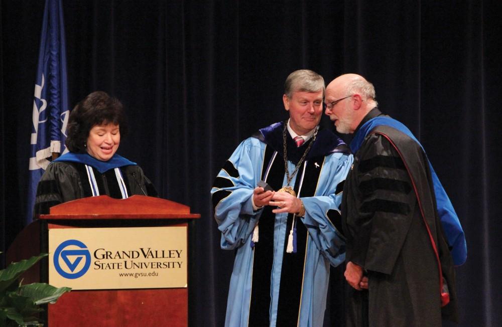 Gayle Davis and President Thomas J. Haas present Theodore Sundstrom with an award for serving an outstanding 40 years at GVSU.