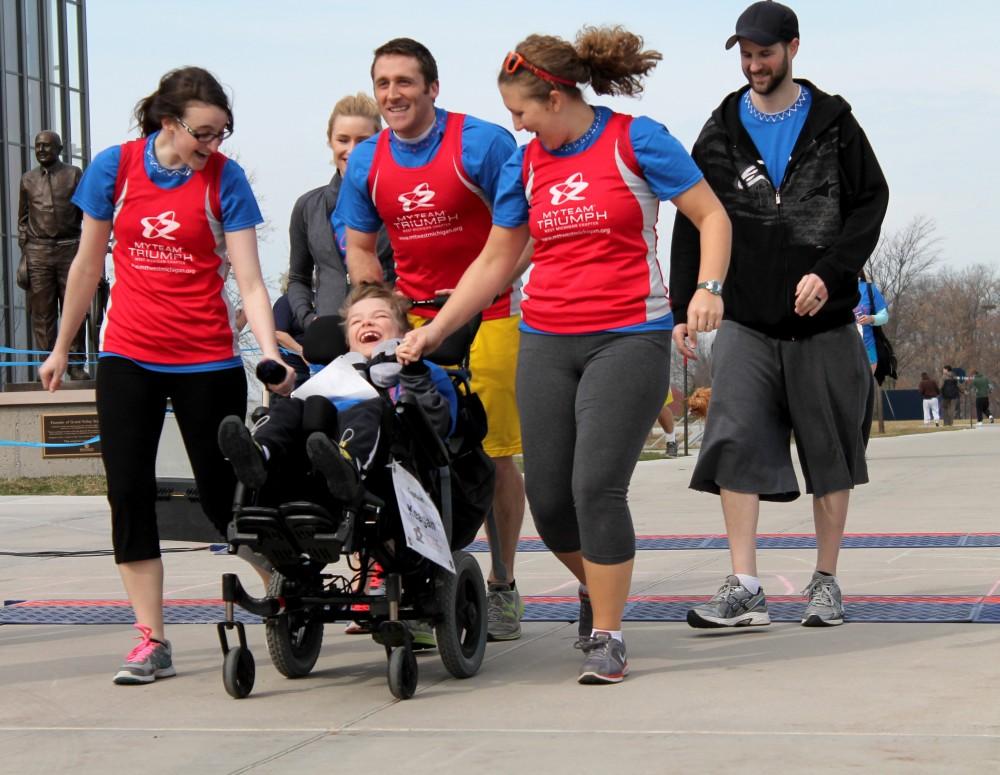 GVL / Grabriella Patti
Grand Valley Physical Therapy students (from left) Emily King, Brett Kain, and Ashley Vandenberg race with eight year old Keagan Curtis and his parents during the Wheel Run Together 5K on Saturday.