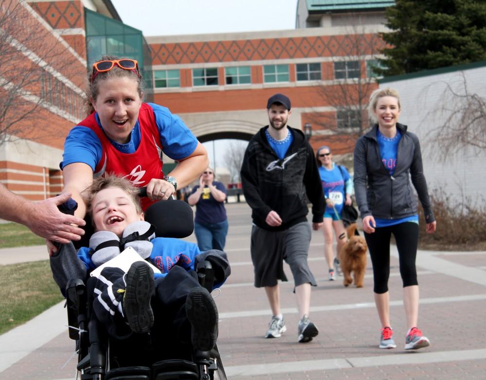 GVL / Gabriella Patti
Grand Valley Physical Therapy student Ashley Vandenberg races with eight year old Keagan Curtis during the Wheel Run Together 5K on Saturday. Keagans parents follow behind to support their son.