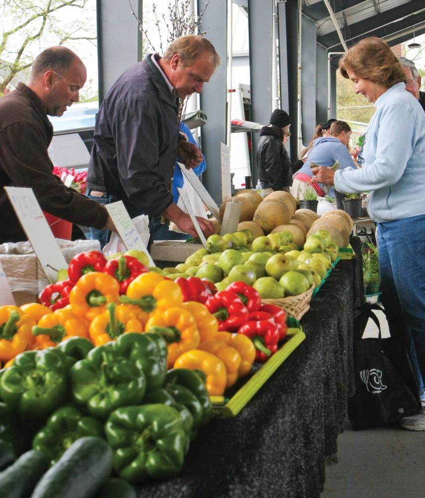 GVL / ArchiveJeff Dykstra of J. Dykstra Produce assists a customer at the Fulton Street Farmers Market during its opening day on Saturday.  