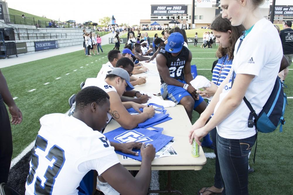 GVL / Kevin Sielaff
Select Grand Valley football players stay stationed at a table to autograph merchandise. The Grand Valley State University athletics department hosts its annual Fan Fest at Lubbers Stadium Thursday, August 28th, 2015. Incoming freshman and athletes alike swarm the football field for games and activities in a "meet and greet" setting. 