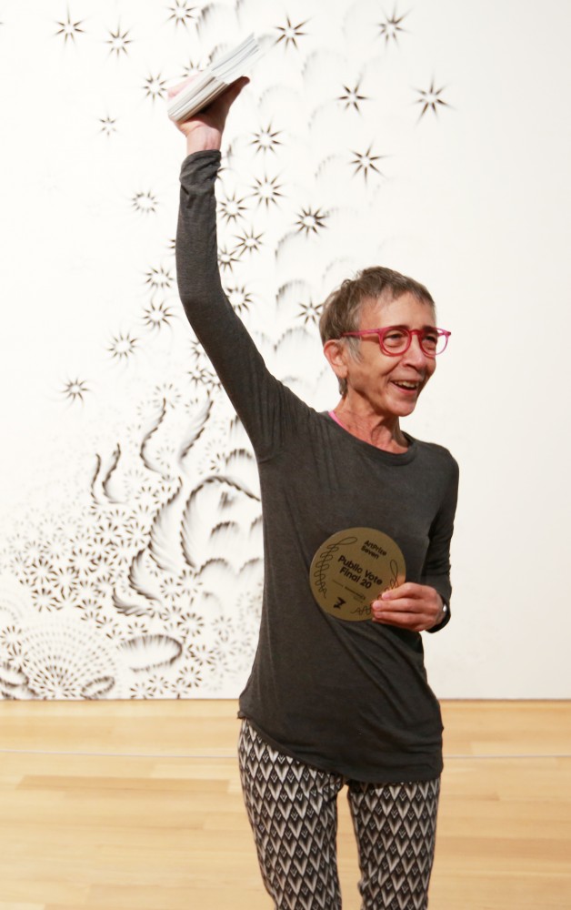 GVL / Kevin Sielaff  
Top 20 artist Judith Braun stands with her charcoal finger painting "As Above" and speaks with spectators. Grand Rapids' annual ArtPrize is held from Sept. 23 - Oct. 1 at various locations around the city. 