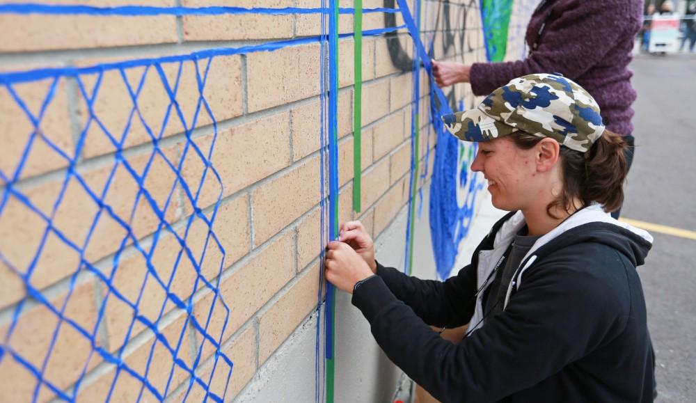 GVL / Kevin Sielaff  
Leah Smith works on her tape drawing on 4 East Fulton Street. Grand Rapids' annual ArtPrize is held from Sept. 23 - Oct. 1 at various locations around the city. 