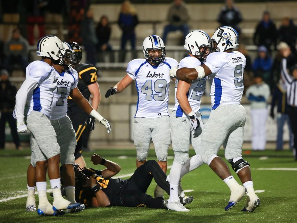 GVL / Kevin Sielaff -  Garrett Pougnet (25) and Matt Judon (9) celebrate over the fallen Brandon Cowie (12). Grand Valley squares off against Michigan Tech Oct. 17 at Lubbers Stadium in Allendale. The Lakers defeated the Huskies with a score of 38-21.