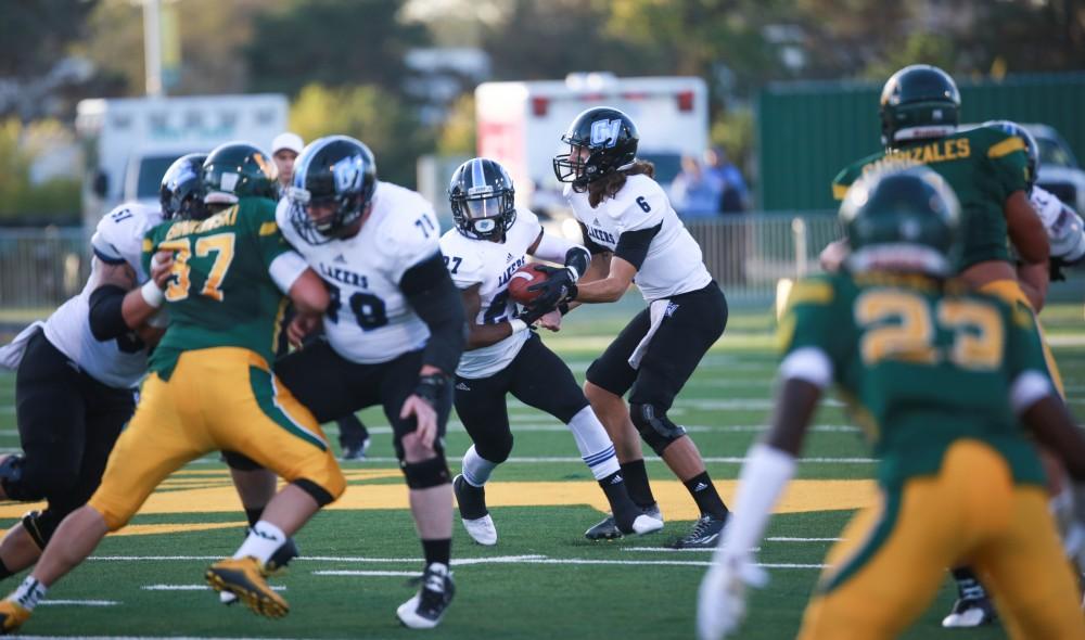 GVL / Kevin Sielaff - Bart Williams (6) hands off the ball to Kirk Spencer (27). Grand Valley squares off against Wayne State University Oct. 11 in Detroit, MI. The Lakers surged to a 38-17 victory vs. the Warriors.