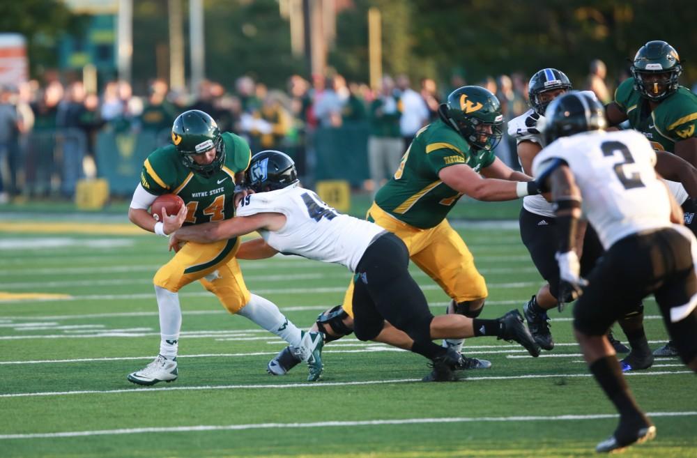 GVL / Kevin Sielaff - Wayne State QB D.J. Zezula (14) is tackled by Collin Schlosser (49).  Grand Valley squares off against Wayne State University Oct. 11 in Detroit, MI. The Lakers surged to a 38-17 victory vs. the Warriors.