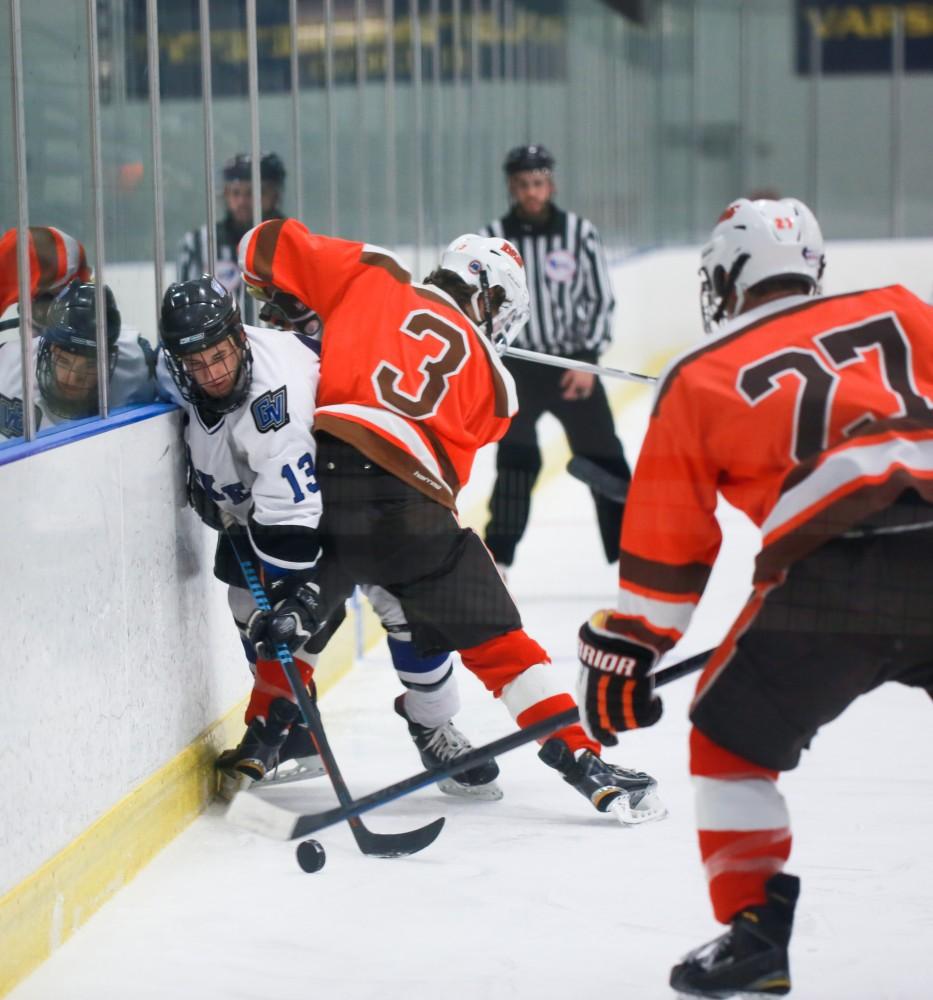 GVL / Kevin Sielaff - Tony Russo (13), pinned up against the boards, manages to get a pass off. Grand Valley's Divison II men's hockey squad squares off against Bowling Green University Oct. 16 at Georgetown Ice Arena.