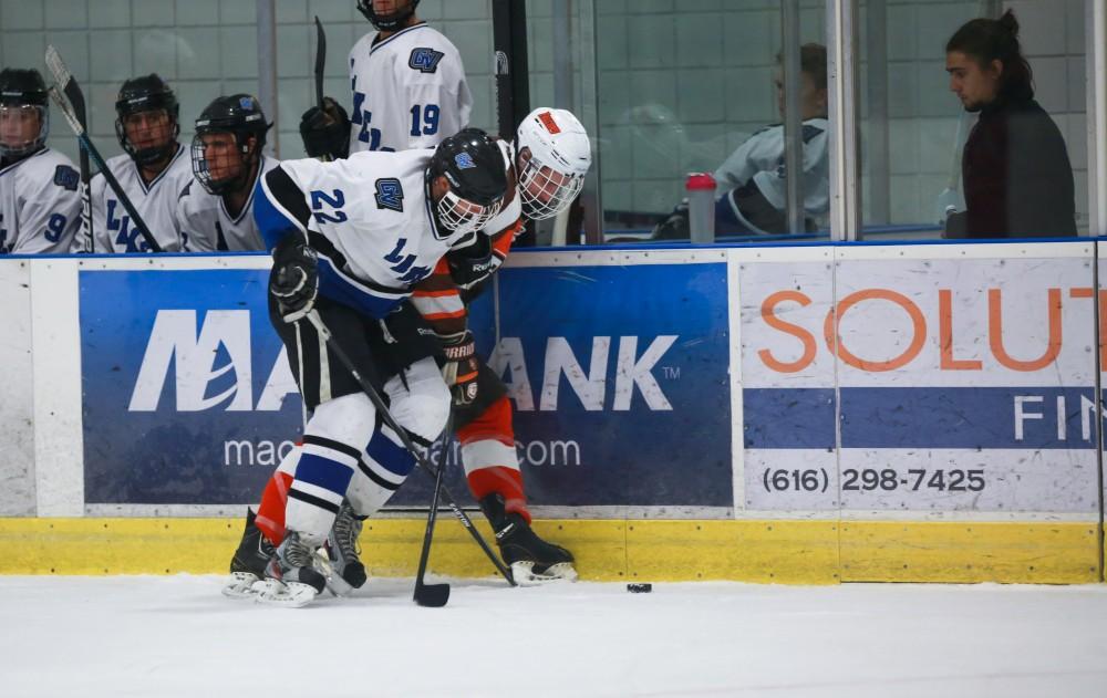 GVL / Kevin Sielaff - Zac Strain (22) fights for the puck against the boards. Grand Valley's Divison II men's hockey squad squares off against Bowling Green University Oct. 16 at Georgetown Ice Arena.