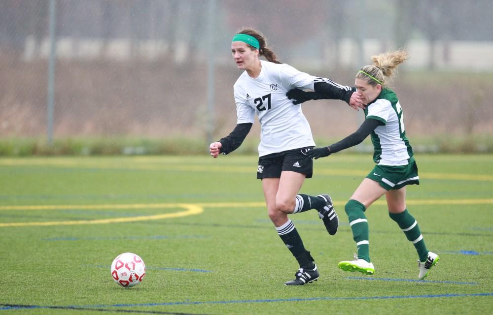 GVL / Kevin Sielaff - Gabby Troy (27) fights for the ball with a State forward.  Grand Valley's women's club soccer team squares off against Michigan State on a rainy Oct. 31. The Lakers were defeated, with a final score of 2-0 in favor of Michigan State.