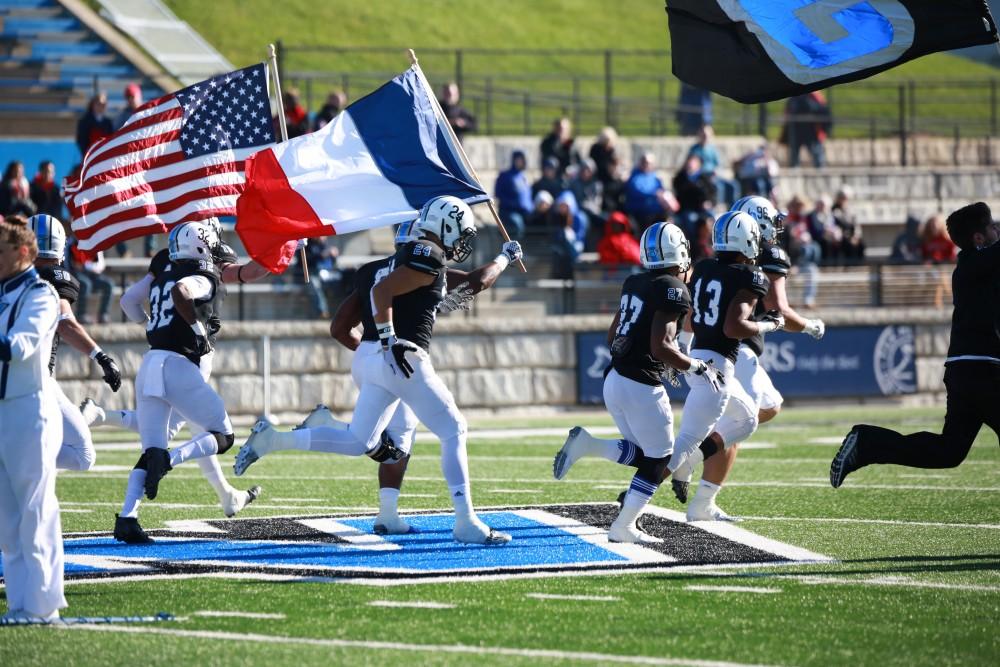 GVL / Kevin Sielaff - Given the happenings in Paris, Matt Judon (9) carries the French flag across the field while the American flag is carried alongside.  Grand Valley squares off against SVSU Nov. 14 in Allendale. The Lakers hold on and win with a final score of 24-17.