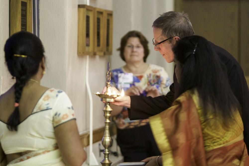 GVL / Sara Carte
Reverend Fred Wooden, lights the candle of the Aarti, a religious tradition, during the Interfaith Diwali Celebration at the Fountain Street Church on Oct. 30.