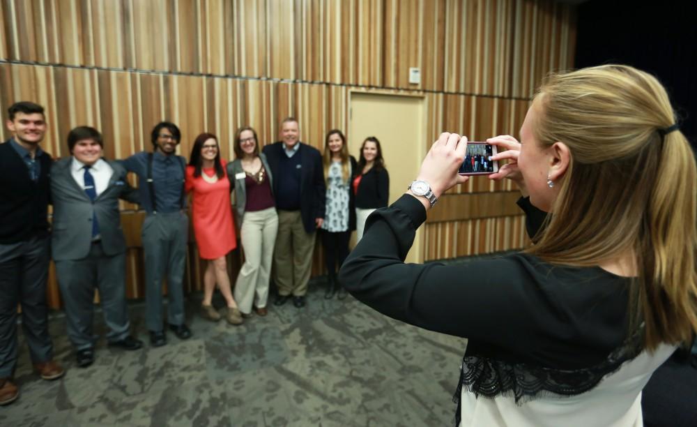 GVL / Kevin Sielaff - Student senate president Maddie Cleghorn takes a photo of Bart Merkle with other members of student senate after the lecture.  Dean of students Bart Merkle speaks at student senate's Last Lecture Nov. 19 at Grand Valley's Mary Idema Pew Library.