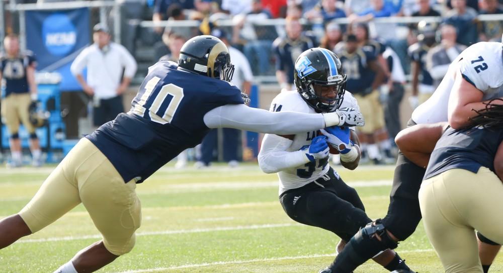 GVL / Kevin Sielaff - Marty Carter (34) seeks a hole in the Shepard defense, but is tackled by Marshall Mundin (10).  The Lakers fall to the Rams of Shepard University with a final score of 34-32 Dec. 12 in Shepardstown, West Virginia.