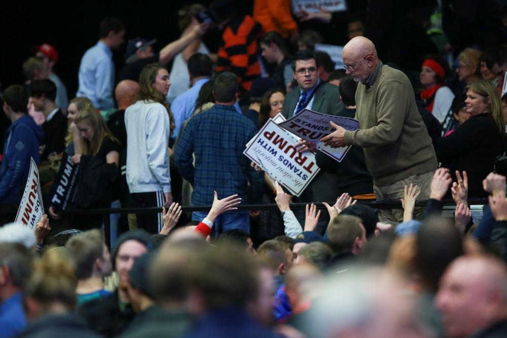 GVL / Kevin Sielaff -  Signs are handed out to those in the audience before the event begins. Republican front runner Donald Trump packs the Deltaplex Arena and Conference Center in downtown Grand Rapids Dec. 21 for a presidential rally. The event boasted the largest crowd ever held at the Deltaplex arena.