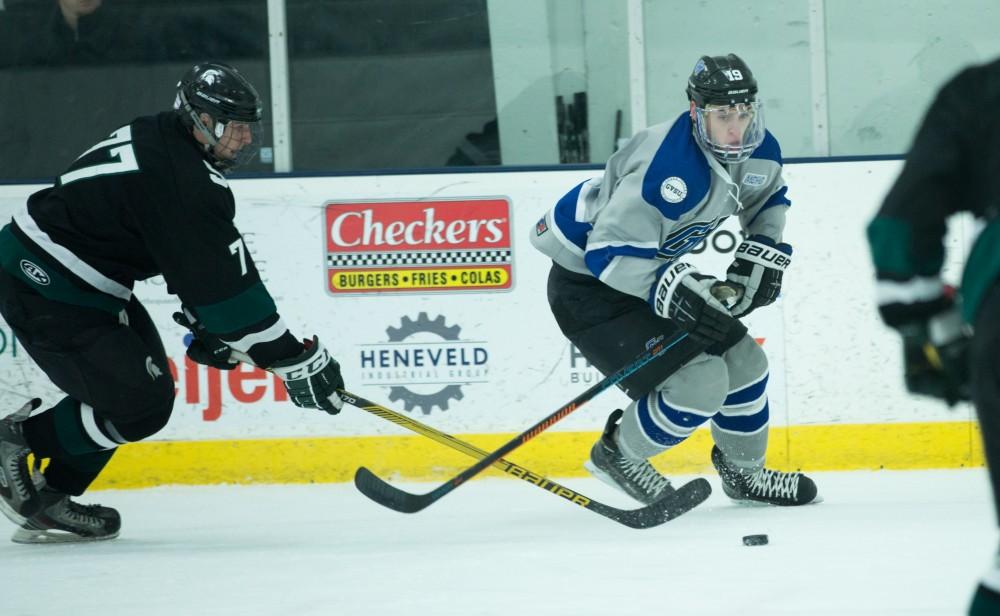 GVL / Kevin Sielaff - Blaine Marney (19) fights for the puck in MSU's zone.  The Lakers’ D3 men’s hockey team blows out Michigan State at Eagle Ice Center in Grand Rapids on Friday, February 12, 2016.