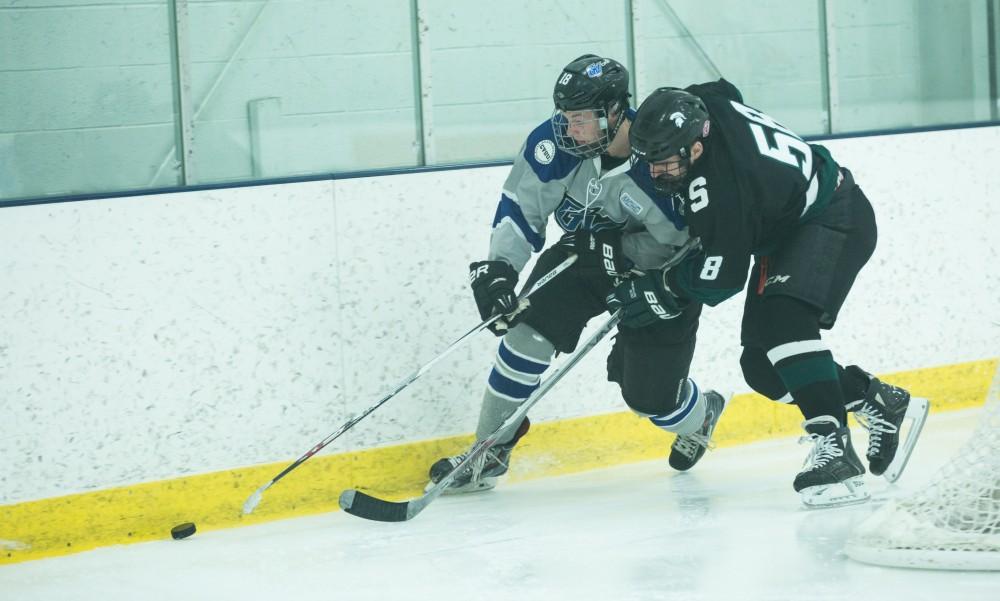 GVL / Kevin Sielaff - Eric White (18) skips the puck off the boards and hunts it down.  The Lakers’ D3 men’s hockey team blows out Michigan State at Eagle Ice Center in Grand Rapids on Friday, February 12, 2016.