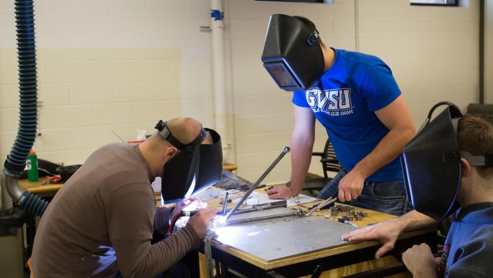 GVL / Kevin Sielaff -  Contracted welder Jake Dykstra performs the finishing touches on all of the vehicle’s a-arms as GVSU student and SAE member Bert Vossler holds the metal in place on Saturday, Feb. 27, 2016 inside the vehicle bay at Grand Valley’s John C. Kennedy Hall of Engineering.