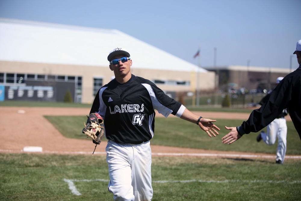 GVL / Emily Frye   
Junior Johnny Nate high fives his teammates between innings against Saginaw Valley State University on Saturday Mar. 26, 2016. 