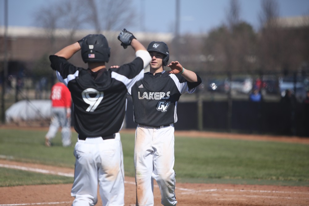 GVL / Emily Frye   
Sophomore Josh Smith and Junior Keith Browning high five after the Lakers first win against Saginaw Valley State University on Saturday Mar. 26, 2016.