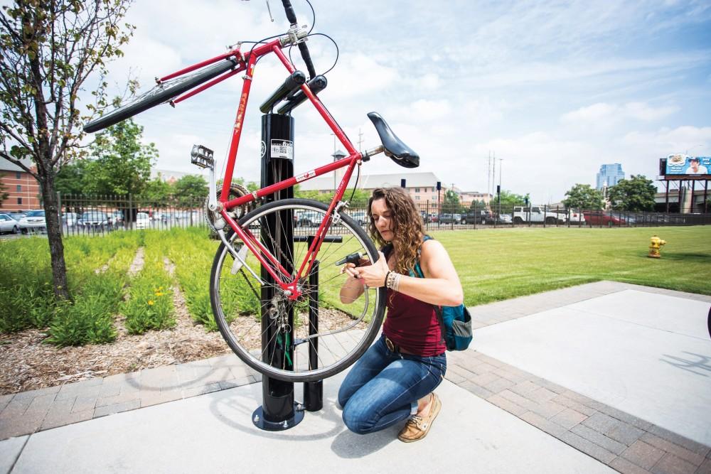 GVL / ArchiveGVSU student, Annie Taccolini, uses one of the new bike repair stations to pump air into her tires on GVSUs Pew campus. The stations are located at the L. William Seidman Center, the Eberhard Center, the Cook-DeVos Center for Health Sciences and Winter Hall.