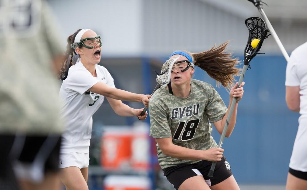 GVL / Kevin Sielaff - Meghan Datema (18) takes a stick to the face while driving on Lake Erie's net. Grand Valley defeats Lake Erie College with a final score of 19-2 on Friday, April 29, 2016 in Allendale. 