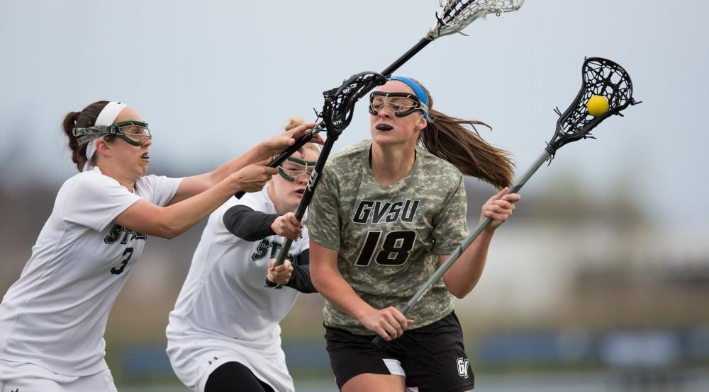 GVL / Kevin Sielaff - Meghan Datema (18), met with resistance, tries to get a shot off on net. Grand Valley defeats Lake Erie College with a final score of 19-2 on Friday, April 29, 2016 in Allendale. 