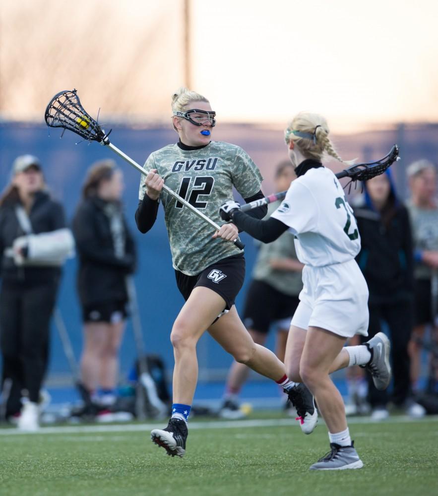 GVL / Kevin Sielaff - Nicki Tague (12) carries the ball up the sideline in Lake Erie's zone. Grand Valley defeats Lake Erie College with a final score of 19-2 on Friday, April 29, 2016 in Allendale. 