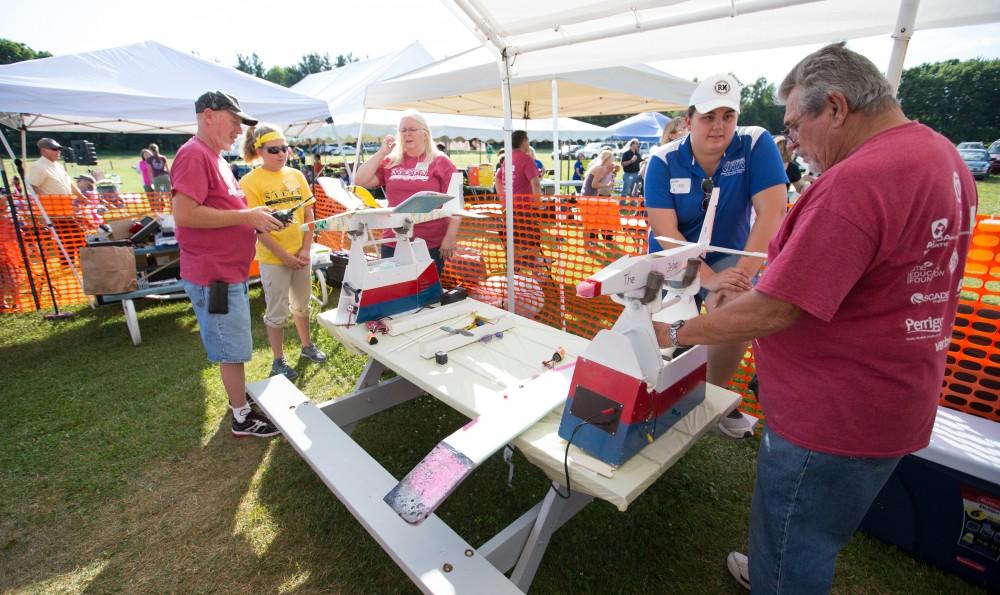 GVL / Kevin Sielaff - Volunteers help repair and assemble plane parts next to the launch site. Students of STEPS (Science, Technology, and Engineering Day Camps) fly planes that they have built during camp at Warped Wings Fly Field in Allendale on Thursday, June 23, 2016. 