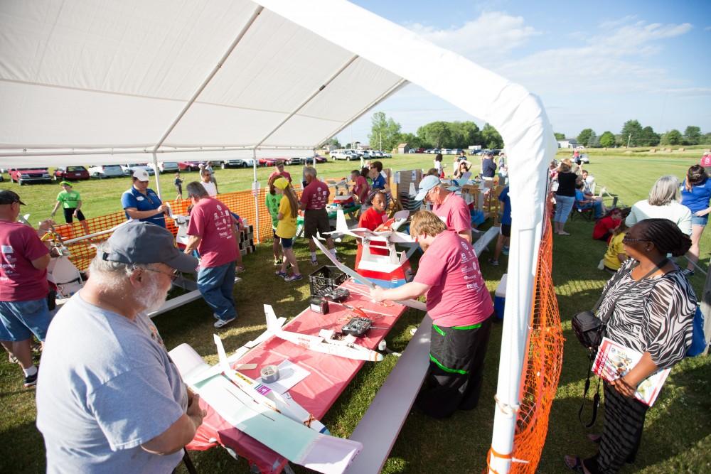 GVL / Kevin Sielaff - Volunteers help repair and assemble plane parts next to the launch site. Students of STEPS (Science, Technology, and Engineering Day Camps) fly planes that they have built during camp at Warped Wings Fly Field in Allendale on Thursday, June 23, 2016. 