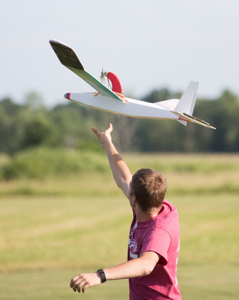 GVL / Kevin Sielaff - A volunteer from Warped Wings helps launch the students' airplanes. Students of STEPS (Science, Technology, and Engineering Day Camps) fly planes that they have built during camp at Warped Wings Fly Field in Allendale on Thursday, June 23, 2016. 